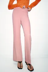 Pantalón de vestir color rosado, tiro bajo, con corte acampanado (flare) y costuras laterales marcadas. Cierre frontal con botón interior y gancho.