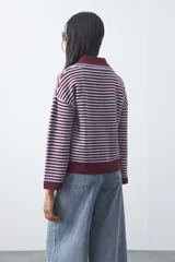 Sweater de punto a rayas horizontales en color bordó y celeste, con cuello polo y mangas largas con puños amplios. Presenta un diseño de calce relajado.