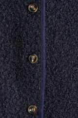 Saco corto de textura tipo sherpa en color azul marino, con cuello redondo y cierre frontal mediante botones. Presenta ribetes en contraste en el escote y la tapeta.