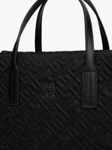 Cartera tipo tote de Tommy Hilfiger, color negro, confeccionada en nailon reciclado con diseño acolchado de monograma TH. Cuenta con dos asas superiores, correa ajustable extraíble, cierre de cremallera y logo metálico frontal.