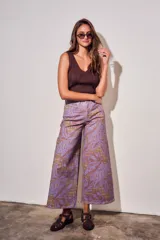Pantalón jean de tiro alto y corte wide leg, con estampado de hojas grandes en tonos morados y fondo con patrón a cuadros.