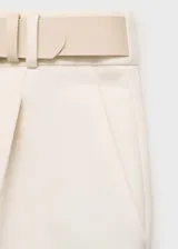 Pantalón de vestir color crema, de tiro medio y corte recto. Incluye cinturón decorativo y bolsillos laterales.