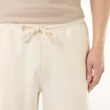 Bermuda blanca de felpa ligera con bolsillos laterales y cintura elástica con cordón ajustable.