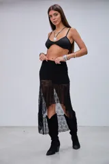 Pollera midi de encaje negro con diseño asimétrico y volados, de tiro medio y corte ajustado en la cadera con caída fluida.