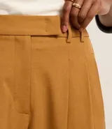 Pantalón de sastrería corte recto confeccionado en crepé, con pliegues delanteros y cintura con detalle cruzado. Presenta un diseño estructurado y elegante.