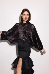 Camisa negra con estampado de hojas en relieve, cuello camisero, mangas anchas y corte cropped.