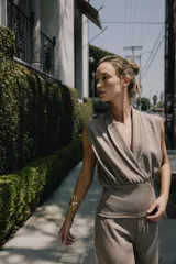 Top sin mangas confeccionado en tejido piqué, con escote cruzado tipo solapa y detalle de pliegues. Presenta una banda ancha ajustada en la cintura y un diseño de hombros caídos.