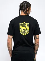 Remera negra de manga corta con cuello redondo y dos escudos amarillos estampados en el pecho: uno con un balón de fútbol rodeado de laureles y otro con un escudo a rayas verticales y estrellas.