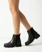 Bota corta de cuero color marrón, con diseño que combina cuero liso y sectores con textura grabada. Presenta una base robusta con taco medio y cierre lateral para facilitar el calce.