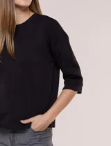 Buzo de calce relajado color negro, confeccionado en modal con cuello redondo clásico, mangas tres cuartos de hombros caídos con puño y ruedo recto.