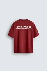 Camiseta de corte relajado (relaxed fit) color rojo oscuro, con cuello redondo, manga corta y bolsillo plastrón en el pecho. Presenta un estampado en la espalda con el texto "SOMETIMES SÍ, SOMETIMES BYE" en blanco.
