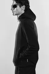 Campera deportiva negra con capucha, cierre frontal y bolsillos laterales con cierre. Confeccionada en tejido funcional efecto neopreno con tecnología DryMove™ para absorber el sudor.