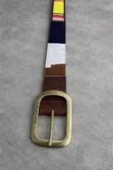 Cinturón de cuero marrón combinado con inserciones de gamuza, pelo vacuno y tejido tipo aguayo de colores. Cuenta con hebilla metálica rectangular envejecida.