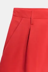 Bermuda de tiro medio color rojo, con trabillas en la cintura, bolsillos laterales y detalle de pinzas en el delantero. Cierre frontal con cremallera y botón.