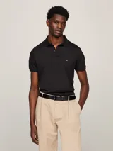 Chomba de hombre Tommy Hilfiger color negro, de corte regular, confeccionada en algodón. Presenta cuello tipo polo, cartera de dos botones y logo bordado en el pecho.