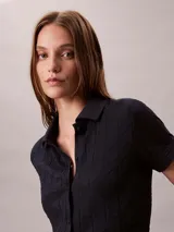 Chomba Calvin Klein de manga corta en color azul marino, con diseño de jacquard geométrico integral, cuello clásico y cierre frontal completo de botones.