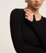 Suéter de punto acanalado color beige, con cuello redondo y mangas largas. Confeccionado en tejido tricot con textura suave y ajuste al cuerpo.