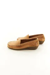 Mocasines de cuero vacuno color beige con acabado mate, costuras visibles artesanales en el empeine y suela de perfil bajo.