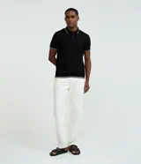 Remera polo blanca de viscosa texturizada con rayas, cuello y puños de mangas cortas en ribana con detalles contrastantes en negro.