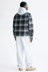 Sobrecamisa de corte relajado en tejido suave con diseño a cuadros. Presenta cuello inglés, cierre frontal con botones a presión, hombros caídos y mangas largas con puños abotonados.