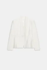 Blazer entallada de color blanco, con cuello sin solapa, manga larga y hombreras. Presenta falsos bolsillos delanteros de vivo y cierre frontal con un botón.