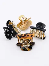 Set de cuatro broches para el pelo tipo pinza, dos de color negro (uno liso y otro con lunares blancos), uno color carey y otro dorado con glitter.