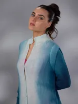 Saco largo de lana merino tejido con diseño jacquard de ramas, de líneas rectas y aberturas laterales, con efecto degradado en tonos azules y blancos, mangas largas con puños entallados y cierre frontal con pequeños botones.