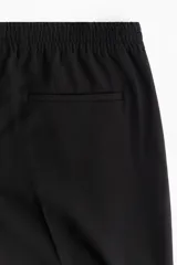 Pantalón de corte relajado con cintura elástica y cordón de ajuste. Presenta pliegues frontales y traseros, bolsillos laterales discretos y un bolsillo trasero insertado.