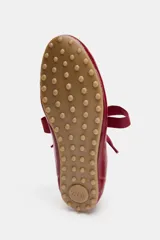 Zapato plano tipo bailarina de estilo deportivo, color rojo charol, con detalle de pespuntes en el cuerpo y suela plana de goma. Cierre mediante lazo de tela en el empeine.