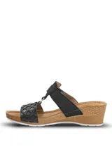 Sandalia Hush Puppies de plataforma baja con diseño de tiras negras. La tira delantera presenta un patrón geométrico calado con pequeñas tachas metálicas, mientras que la tira superior cuenta con un cierre de velcro para un ajuste personalizado. La plantilla es de color marrón y la suela tiene un acabado texturizado que simula madera.