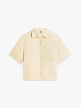 Camisa de manga corta Tommy Hilfiger de corte amplio y color beige, confeccionada en puro lino. Presenta cuello inglés, cierre frontal de botones, un bolsillo de parche en el pecho con el logo bordado y hombros ligeramente caídos.