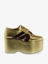 Zapatilla deportiva con plataforma de gran volumen, color dorado metálico, con cordones marrones y franjas laterales en charol marrón oscuro.