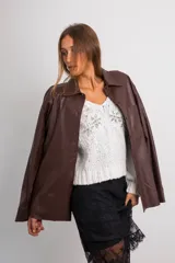 Camisa oversize de cuerina color marrón, con cuello clásico, cierre frontal con botones y bolsillo de parche en el pecho.