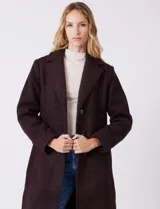 Tapado largo de bouclé color marrón oscuro, con silueta entallada que termina en evasé. Tiene cuello de solapa amplia, cierre frontal con tres botones a tono y bolsillos funcionales con solapa. Incluye forro interno a tono.