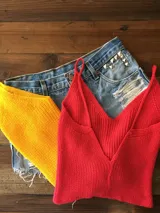 Conjunto de tops de hilo, uno rojo y otro amarillo, junto a un short de jean con tachas.