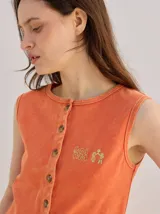 Musculosa MUTMA Trebola de silueta recta confeccionada en tejido de punto color gris con efecto lavado. Posee cierre frontal con botones, detalle de bordado en el pecho y terminación festoneada en el ruedo y las sisas.