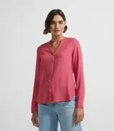 Camisa de manga larga confeccionada en mezcla de viscosa y lino, con cuello tipo padre, escote en V y cierre frontal con botones. Presenta un diseño con dobladillo tipo mullet, siendo más largo en la parte posterior.