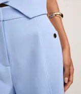 Short sastre de cintura alta, color blanco, con bolsillos laterales y detalles de tachuelas metalizadas.
