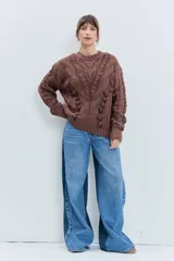 Sweater de punto color celeste, con diseño de trenzas y detalles de cordones entrelazados en el frente y las mangas. Presenta cuello redondo y puños acanalados.