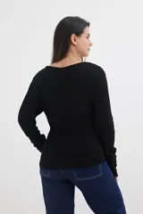 Sweater negro de tejido de punto acanalado, con escote en V y cierre frontal con cremallera circular.