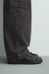 Zapatilla negra de cordones, con parte superior lisa y cordonera oculta. Posee suela con volumen a tono.