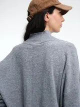 Sweater de tejido de punto color marrón, con cuello alto, corte amplio y tajos laterales en el ruedo. Presenta una costura vertical central en el frente y mangas largas con puños acanalados.