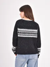 Buzo de tejido de punto en color negro con efecto jaspeado y diseño geométrico en blanco en la parte superior del pecho y en los puños. Presenta cuello redondo y mangas largas con terminaciones en tejido acanalado.