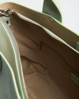 Cartera tipo tote color verde menta, confeccionada en símil cuero, con doble asa de mano y correa larga ajustable y desmontable. Cuenta con el logotipo de la marca grabado en plateado en el frente.