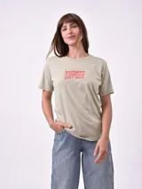 Remera de manga corta color verde claro, con cuello redondo y un pequeño estampado de texto en color rojo en el pecho.