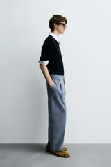 Pantalón de hombre color azul grisáceo, estilo balloon fit, confeccionado en mezcla de algodón y lino. Presenta pliegues en el delantero, cierre frontal con botón y cremallera, bolsillos laterales y bolsillos traseros de plastrón.