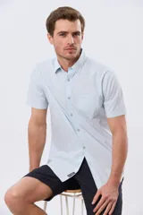 Camisa lisa de algodón azul marino, de manga corta, con cuello camisero, cierre frontal de botones y un bolsillo aplicado en el pecho.