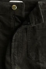 Pantalón acampanado de pana color negro, de tiro alto, con cierre de botón y bolsillos de parche delanteros y traseros.