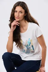 Remera blanca de manga corta y cuello redondo, con estampa frontal ilustrativa de un paisaje urbano con escalinatas en tonos azules y tierra.