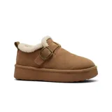 Zapato de cuero tipo zueco con plataforma, forrado internamente con corderito sintético. Presenta una tira ajustable con hebilla metálica en el empeine y un tirador en el talón.